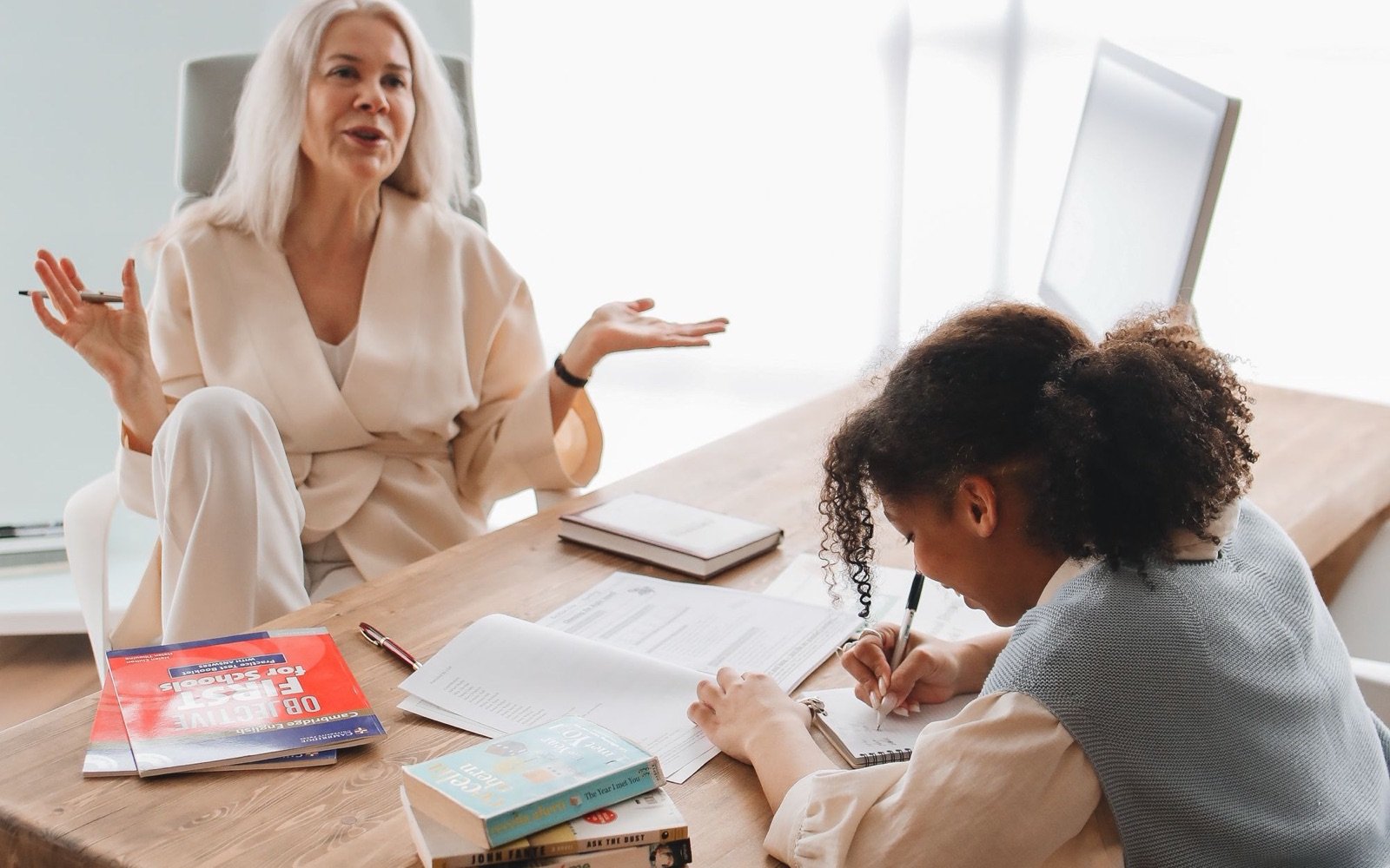A tutor talking a point through while her student works at the table