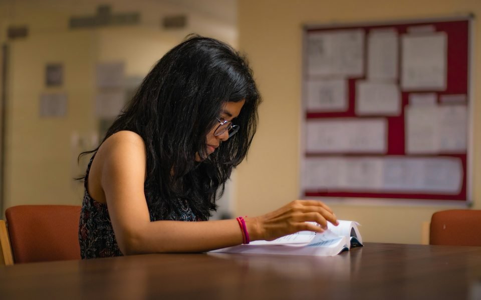 A student in glasses reading through her paper at a classroom table