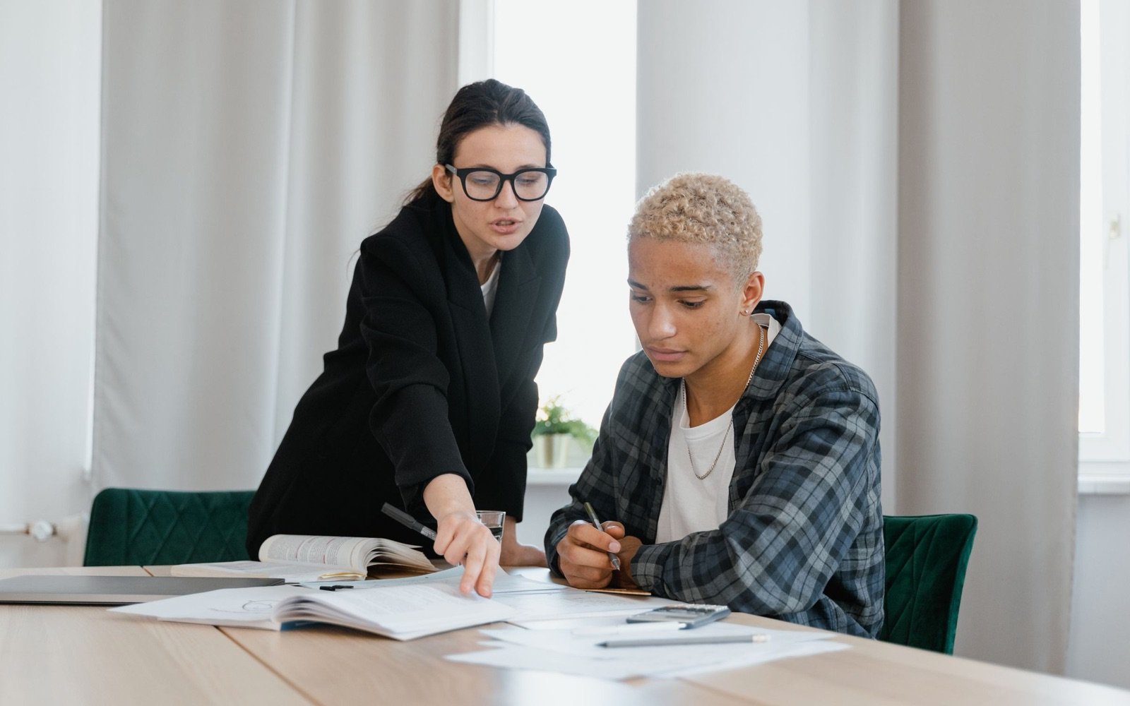 A university counsellor guiding a student through his plans at a table